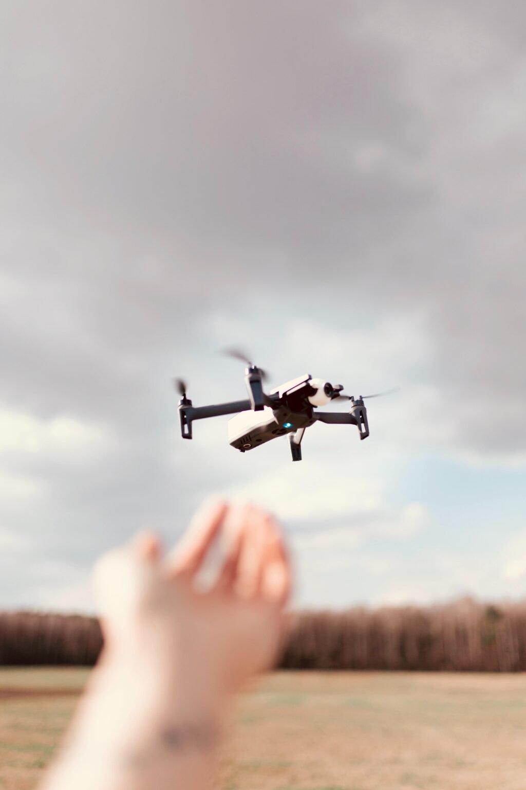A black quadcopter drone over a cloudy sky